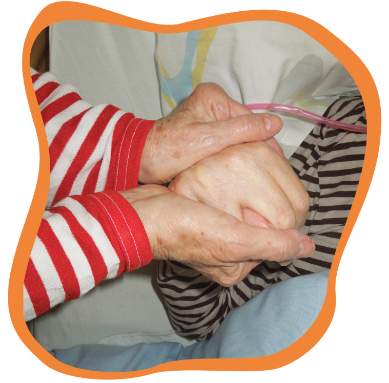 Ein Cliniclown hält zur Unterstützung die Hand einer Patientin